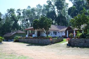a house with a retaining wall and flowers in front of it at Whispering Meadows By Dazzle Destinations - Coorg in Somvārpet +17 photos
