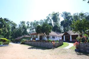 a house with a retaining wall and flowers in a yard at Whispering Meadows By Dazzle Destinations - Coorg in Somvārpet