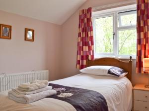 a bedroom with a bed with towels on it at Honeysuckle Cottage in Minsterley