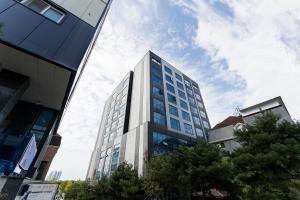 a tall white building with blue windows at 브라운도트호텔 인천 송도 Browndot Hotel Incheon Songdo in Incheon