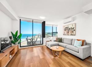 a living room with a couch and a tv at Seaside Luxe - L8 - Local Eats, Walks, Swims, CBD in Newcastle