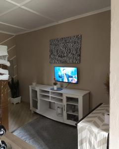 a living room with a television on a white cabinet at Masai Apartments Diani in Ukunda
