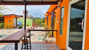 an orange building with a wooden table and stools at Thung Setthi Homestay&Cafe5 in Chiang Dao