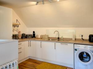 a kitchen with white cabinets and a washer and dryer at 3 Old Posting Stables in Gatehouse of Fleet