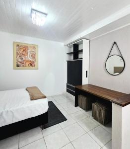 a bedroom with a bed and a mirror and a desk at Studio Central - Climatizado - Prático in Erval dʼOeste
