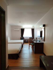 a hotel room with two beds and a desk at Hotel Seri Malaysia Port Dickson in Port Dickson