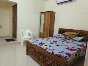 a bedroom with a bed and a white chair at KSM Rooms in Tiruvannāmalai