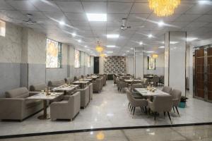 a dining room with tables and chairs and chandeliers at Minta Hotel and Banquet in Noida