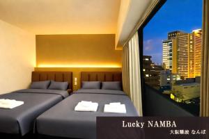 two beds in a room with a view of a city at Lucky NAMBA 大阪難波 なんば in Osaka
