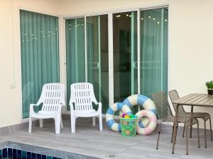a group of chairs sitting on a porch with a pool at Buddy pool villa in Nong Prue