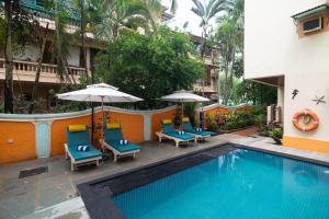 a swimming pool with chairs and umbrellas next to a building at Victor Exotica An Indy Resort in Candolim