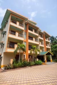 a large building with palm trees in front of it at Victor Exotica An Indy Resort in Candolim