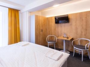a room with a bed and two chairs and a table at Hotel Svět in Třeboň