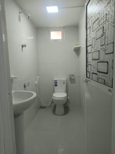 a white bathroom with a toilet and a sink at Diving Nest in Trincomalee