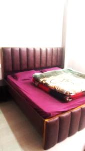 a bed in a room with purple sheets and a suitcase on it at Hotel Venkatesh in Badrinath