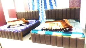 two beds sitting in a room with a couch at Hotel Venkatesh in Badrinath