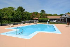 a swimming pool with tables and chairs in a yard at Quality Inn Raynham - Taunton in Raynham