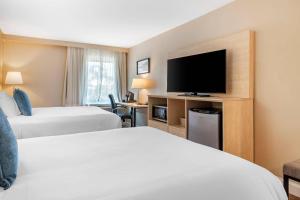 a hotel room with two beds and a flat screen tv at Casco Bay Hotel Portland Airport - Maine Mall, an Ascend Collection Hotel in South Portland