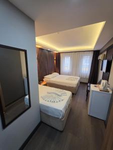 a hotel room with two beds and a mirror at Gizem Pansiyon in Çanakkale