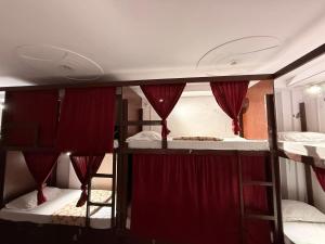 two bunk beds in a room with red curtains at Cozy Inn Hostel in New Delhi