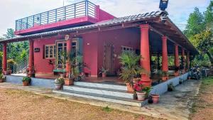a red house with potted plants in front of it at Aksha Homestay in Sakleshpur