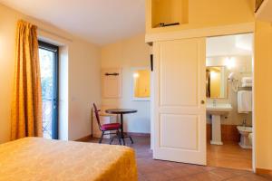 a bedroom with a bed and a table and a bathroom at Locanda Il Gallo in Greve in Chianti