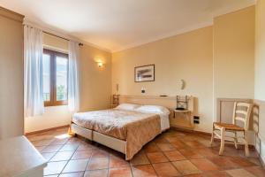 a bedroom with a bed and a chair and a window at Locanda Il Gallo in Greve in Chianti