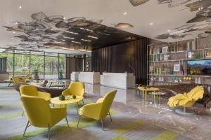 a lobby with yellow chairs and tables and shelves at Citadines Millennium Ortigas Manila in Manila