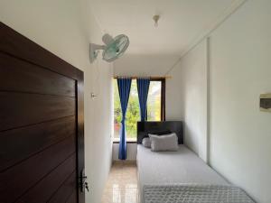 a small bedroom with a bed and a window at Ibu ana quest house in Tabanan