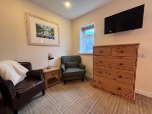 a bedroom with a dresser and a tv and a chair at The Ullapool Rooms in Ullapool