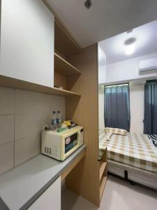 a small kitchen with a microwave and a bed at Osaka Riverview Apartment PIK 2 in Rawalumpang +8 photos