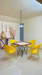 a dining room with a table and yellow chairs at Shubh causy 4bhk villa in Lonavala