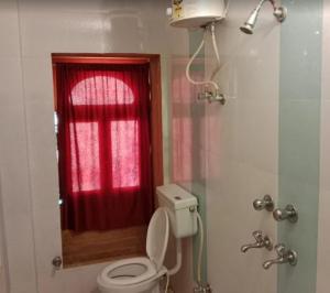 a bathroom with a toilet and a red curtain at The Jeet Mahal Hotel in Jaisalmer