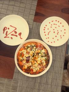 a pizza in a bowl on a table with three plates at Hotel Yashoday in Kekri