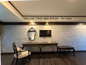 a room with a table and a tv on a wall at I Calm Resort Cha Am in Cha Am