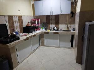 a kitchen with white cabinets and a tiled floor at شقق الخيالي 1 in Tan-Tan