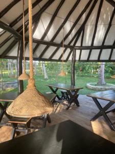 a group of tables and swings in a tent at Aji fruit farm cottage peaceful lakeside farm stay with sunrise views 01 in Embilipitiya