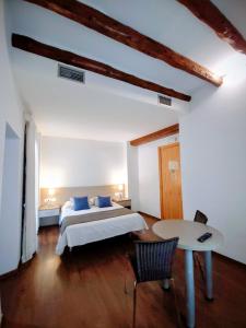 a bedroom with a bed and a table in it at Hostal Agrobotiga 7 de Ribera in Móra d'Ebre