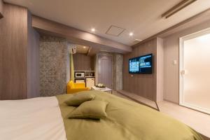 a bedroom with a large bed with a television on the wall at HOTEL ARIA-Yokohama Kannai in Yokohama