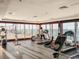 a woman exercising on treadmills in a gym at FIRST CLASS Studio Pacific Shores Retreat in Ras al Khaimah