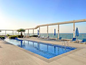 a swimming pool with chairs and the ocean in the background at FIRST CLASS Studio Pacific Shores Retreat in Ras al Khaimah