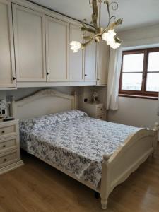 a bedroom with a bed and white cabinets and a chandelier at Casa vacanze tortoi in Candide