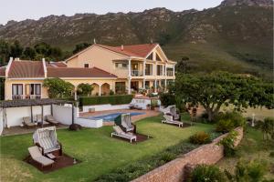 a house with a yard with chairs and a pool at Apricot Gardens Guesthouse in Gordonʼs Bay