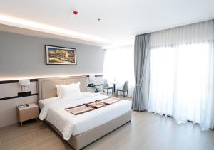 a bedroom with a large white bed and a table at LN Hotel & Residence in Phnom Penh