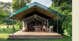a tent with a table and chairs in it at Oloimala Mara Camp in Gatunga