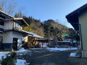 a house with snow on the ground next to a building at つむぐ家2 in Ueda