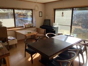 a dining room with a table and chairs and a piano at つむぐ家2 in Ueda