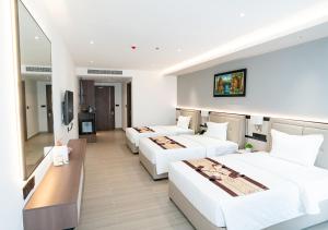 a hotel room with three beds and a table at LN Hotel & Residence in Phnom Penh