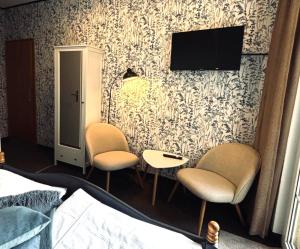 a bedroom with two chairs and a tv on a wall at Am Wasserturm Pension in Bad Muskau