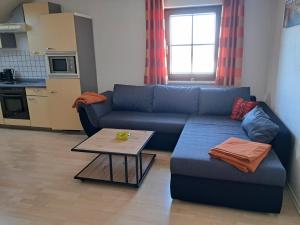 a living room with a blue couch and a table at Haus Probst in Bischofsmais